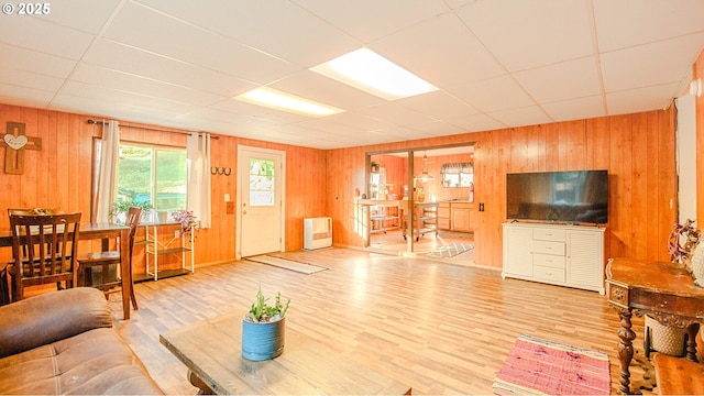 living room featuring hardwood / wood-style floors, wooden walls, and a paneled ceiling