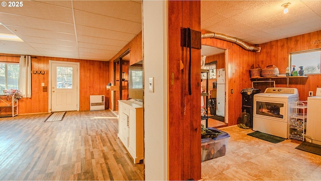 interior space with heating unit, wooden walls, light hardwood / wood-style floors, and washer and dryer