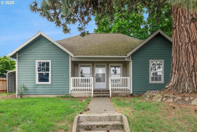 bungalow featuring a porch, roof with shingles, and a front yard