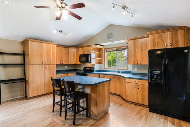 kitchen with black appliances, lofted ceiling, rail lighting, a sink, and dark countertops