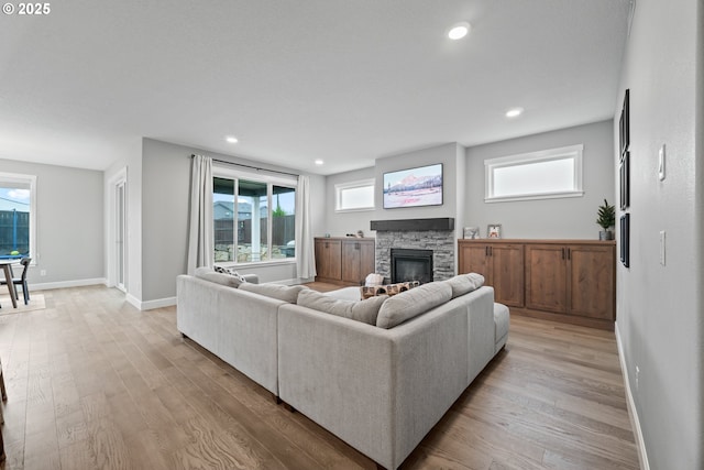 4342 S 16th Way, Ridgefield, WA 98642 - living area with light wood-style floors, a stone fireplace, baseboards, healthy amount of natural light, and recessed lighting