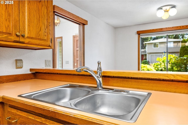 kitchen with brown cabinetry, a sink, and light countertops