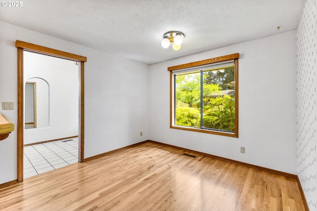 empty room with baseboards, visible vents, and wood finished floors