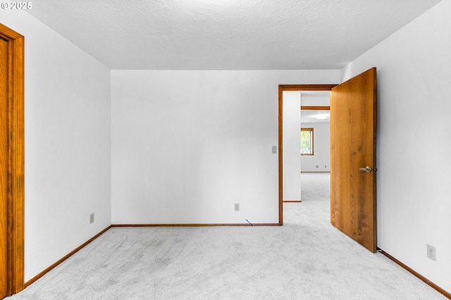 spare room featuring baseboards, carpet, and a textured ceiling
