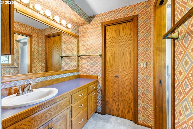 bathroom featuring vanity and wallpapered walls