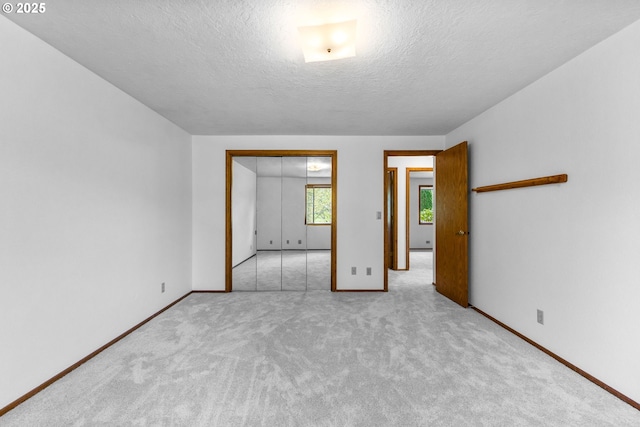 unfurnished bedroom featuring a textured ceiling, baseboards, and carpet