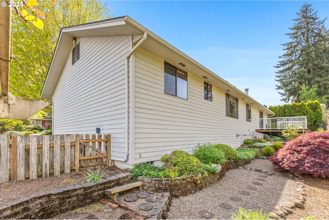 view of side of home featuring fence and a deck