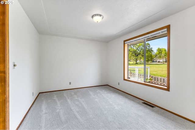 spare room with baseboards, light carpet, and visible vents