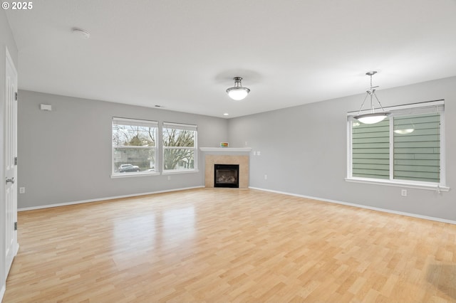 unfurnished living room with a fireplace, baseboards, and light wood-type flooring