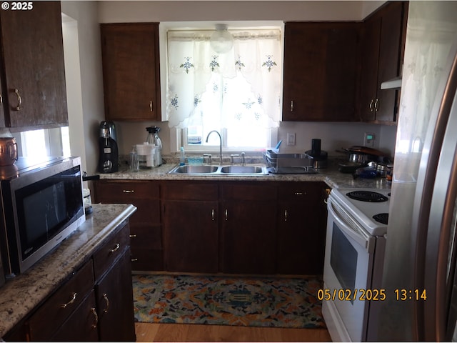537 Hall St, Woodburn, OR 97071 - kitchen with dark brown cabinetry, appliances with stainless steel finishes, light stone countertops, a sink, and under cabinet range hood