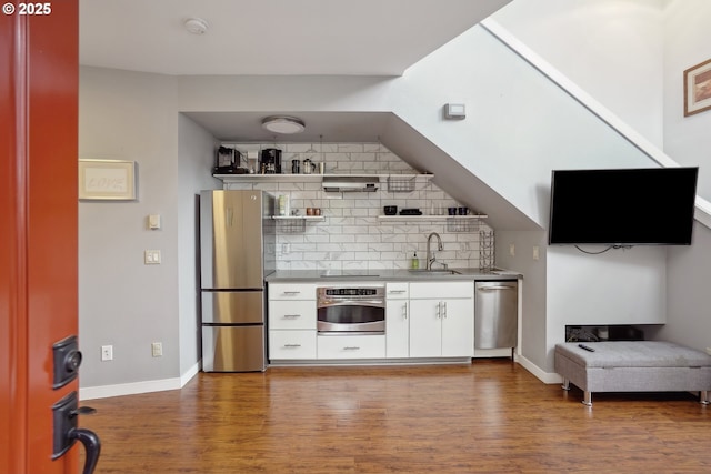 bar area with appliances with stainless steel finishes, a sink, wood finished floors, and tasteful backsplash