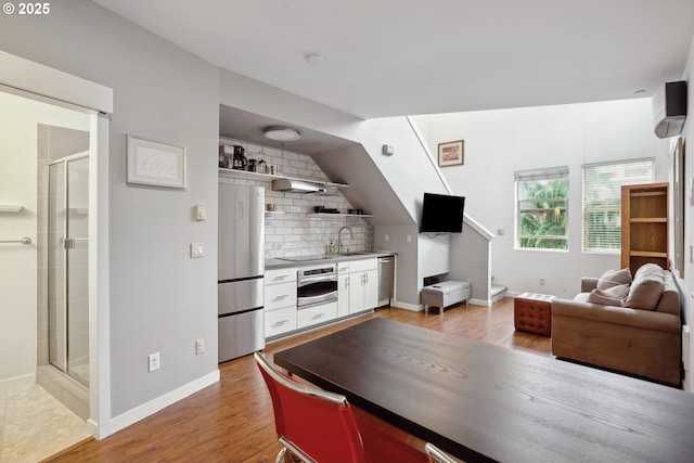kitchen featuring appliances with stainless steel finishes, open shelves, decorative backsplash, baseboards, and a sink