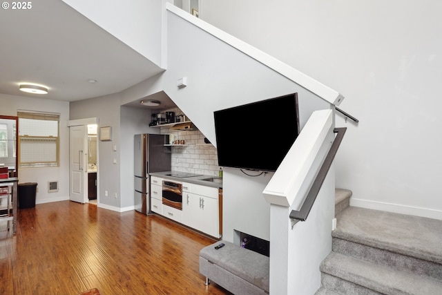 unfurnished living room with stairway, baseboards, and wood finished floors