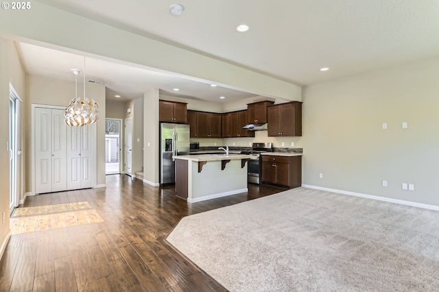 7156 NW Abigail Ter, Portland, OR 97229 - kitchen with dark brown cabinets, an inviting chandelier, a breakfast bar area, stainless steel appliances, and under cabinet range hood