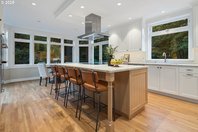 3505 SW Beaverton Ave, Portland, OR 97239 - kitchen featuring island exhaust hood, a kitchen island, light wood-style flooring, white cabinets, and recessed lighting