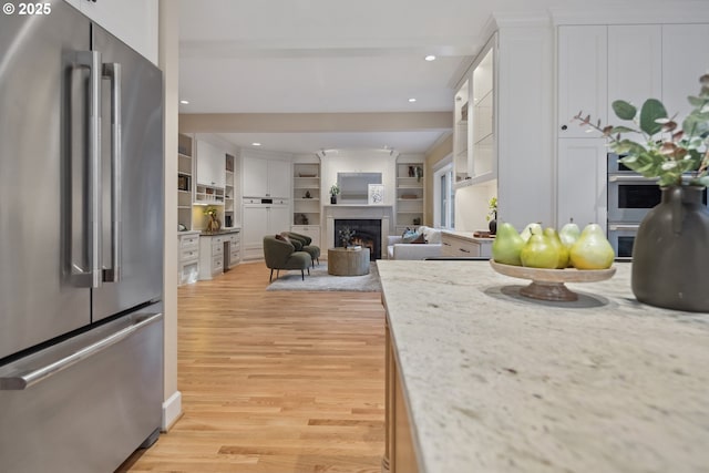 3505 SW Beaverton Ave, Portland, OR 97239 - kitchen with freestanding refrigerator, light wood-style floors, white cabinetry, glass insert cabinets, and recessed lighting