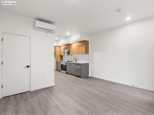 kitchen with stainless steel appliances, an AC wall unit, light countertops, modern cabinets, and backsplash