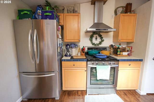 kitchen with tile countertops, stainless steel appliances, wall chimney range hood, and dark wood-style floors