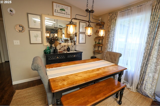 dining space featuring baseboards, vaulted ceiling, and wood finished floors