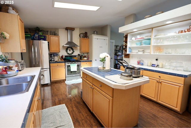 kitchen with tile countertops, stainless steel appliances, dark wood-type flooring, a sink, and wall chimney exhaust hood