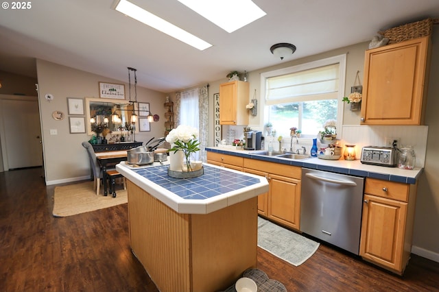 kitchen featuring tile countertops, vaulted ceiling with skylight, dark wood-style flooring, a sink, and stainless steel dishwasher