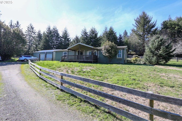 view of front facade with an attached garage, a wooden deck, fence, and a front yard