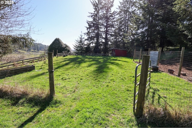 view of yard with a rural view, fence, and an outdoor structure