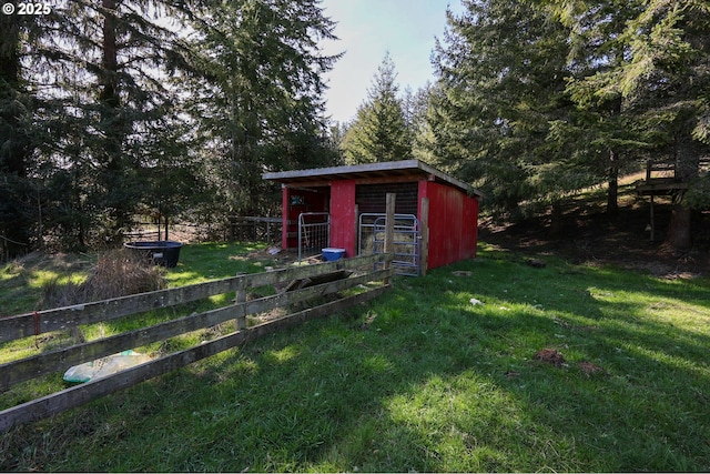 view of outdoor structure with fence and an outbuilding