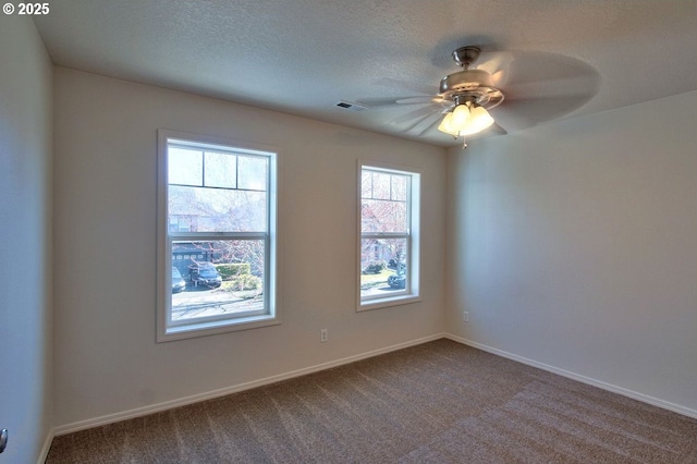 empty room with visible vents, a textured ceiling, ceiling fan, and dark colored carpet