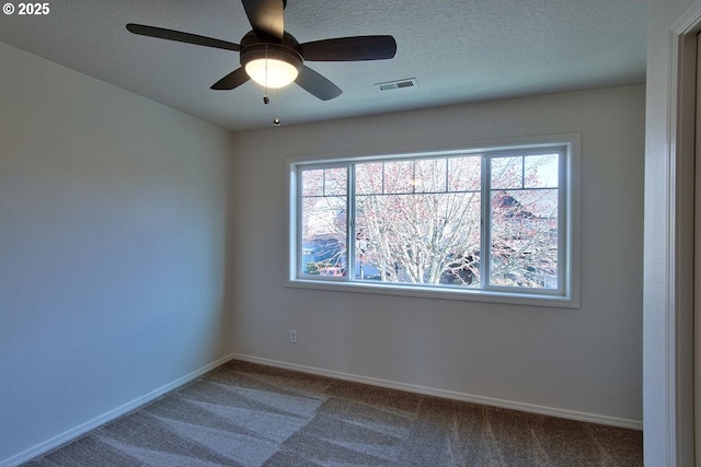 carpeted empty room featuring visible vents, plenty of natural light, a textured ceiling, and baseboards