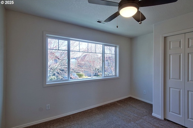 unfurnished bedroom with baseboards, visible vents, a closet, a textured ceiling, and carpet flooring