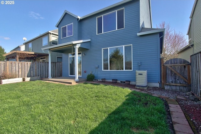 back of property with a gate, central AC unit, a lawn, and fence