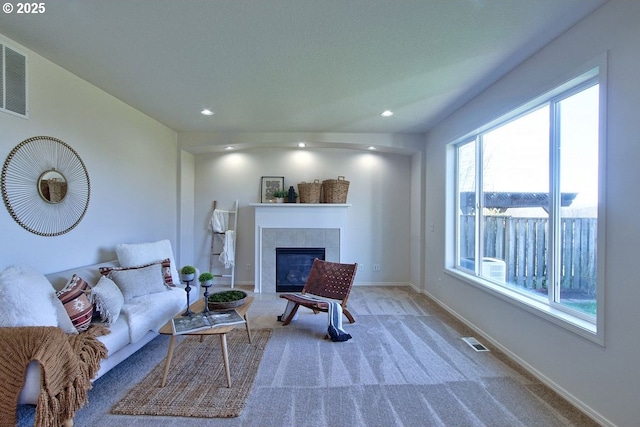 living area featuring visible vents, a tiled fireplace, recessed lighting, carpet flooring, and baseboards