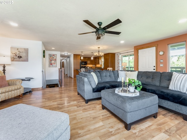living area with plenty of natural light, ceiling fan with notable chandelier, and light wood-type flooring