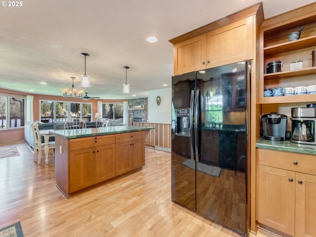 kitchen with plenty of natural light, light wood-style flooring, black fridge with ice dispenser, and a chandelier