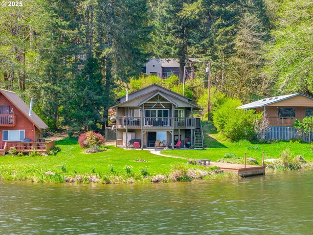 back of property with a forest view, a lawn, a deck with water view, and stairs