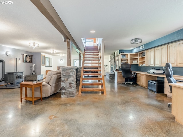 interior space featuring stairway, built in desk, finished concrete flooring, and a wood stove