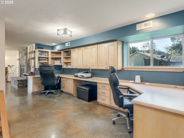 office with built in desk, concrete floors, a textured ceiling, and visible vents
