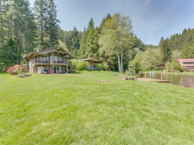 view of yard with a wooded view, a deck with water view, and stairs