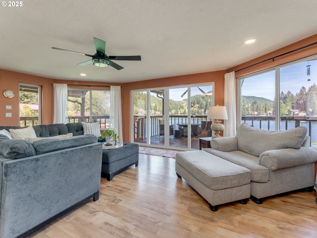 living area featuring ceiling fan, recessed lighting, a water view, and light wood-style floors