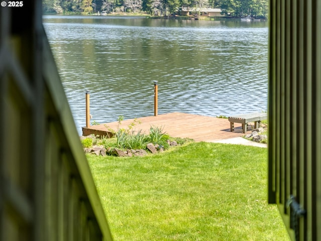 view of dock with a water view and a yard