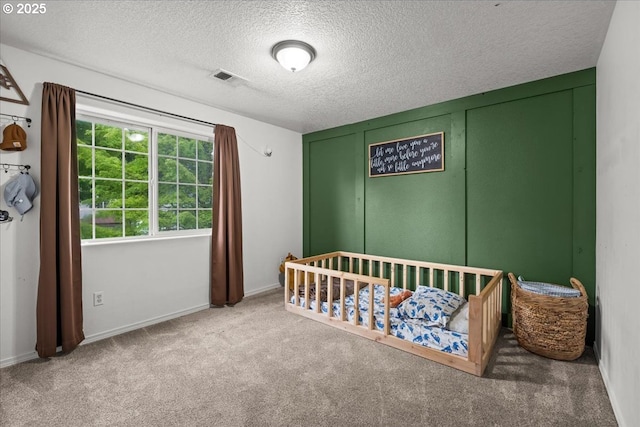 bedroom featuring carpet flooring, a textured ceiling, baseboards, and a nursery area
