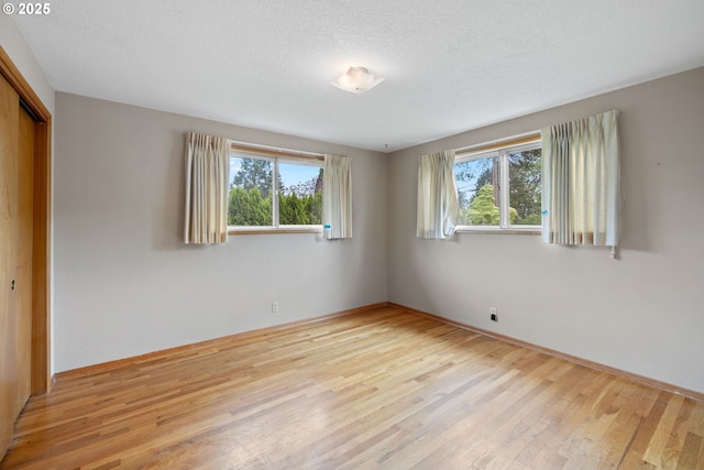 1627 NE 143rd Ave, Portland, OR 97230 - unfurnished bedroom featuring multiple windows, a closet, light wood-type flooring, baseboards, and a textured ceiling