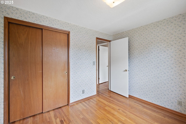 1627 NE 143rd Ave, Portland, OR 97230 - unfurnished bedroom with wallpapered walls, light wood-type flooring, baseboards, and a closet