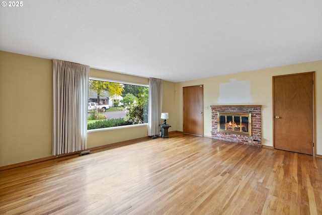 1627 NE 143rd Ave, Portland, OR 97230 - unfurnished living room with wood finished floors, a brick fireplace, and baseboards
