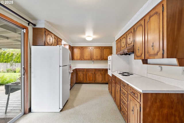 1627 NE 143rd Ave, Portland, OR 97230 - kitchen with white appliances, brown cabinets, under cabinet range hood, light countertops, and light colored carpet