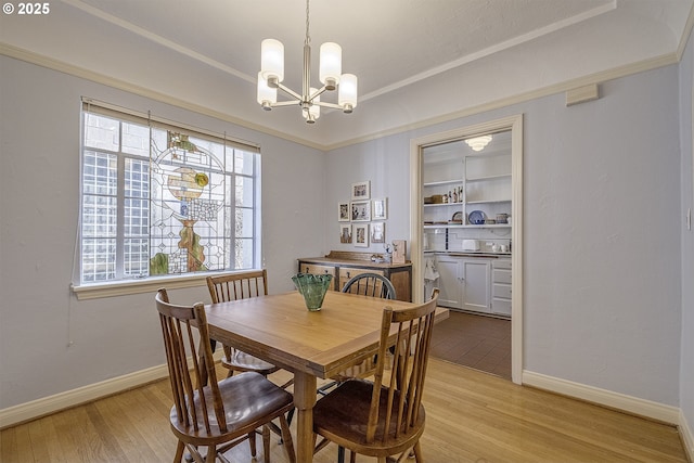 dining area featuring baseboards, ornamental molding, light wood finished floors, and a notable chandelier