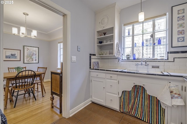 kitchen with an inviting chandelier, a wealth of natural light, tasteful backsplash, and white cabinets