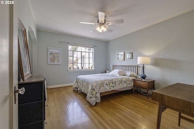 bedroom featuring crown molding, a ceiling fan, baseboards, and light wood-style flooring