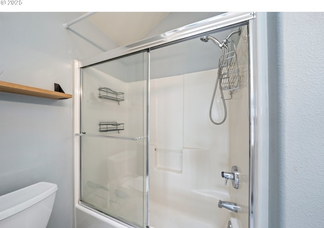bathroom with combined bath / shower with glass door and toilet